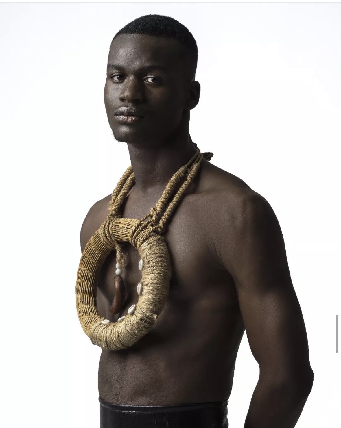 Designed by Kgosi Gift — a woven jute and cowrie shell ringed neckpiece worn against bare skin, sculptural and ceremonial