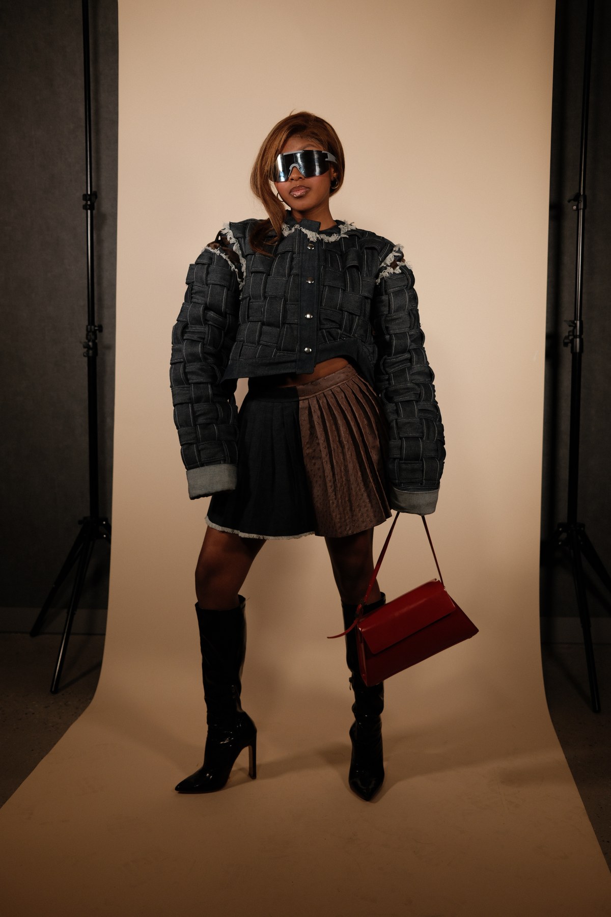 Designed by Mihlali Madikane — a woven denim cropped jacket over a two-tone pleated mini, worn with reflective visor and knee-high boots