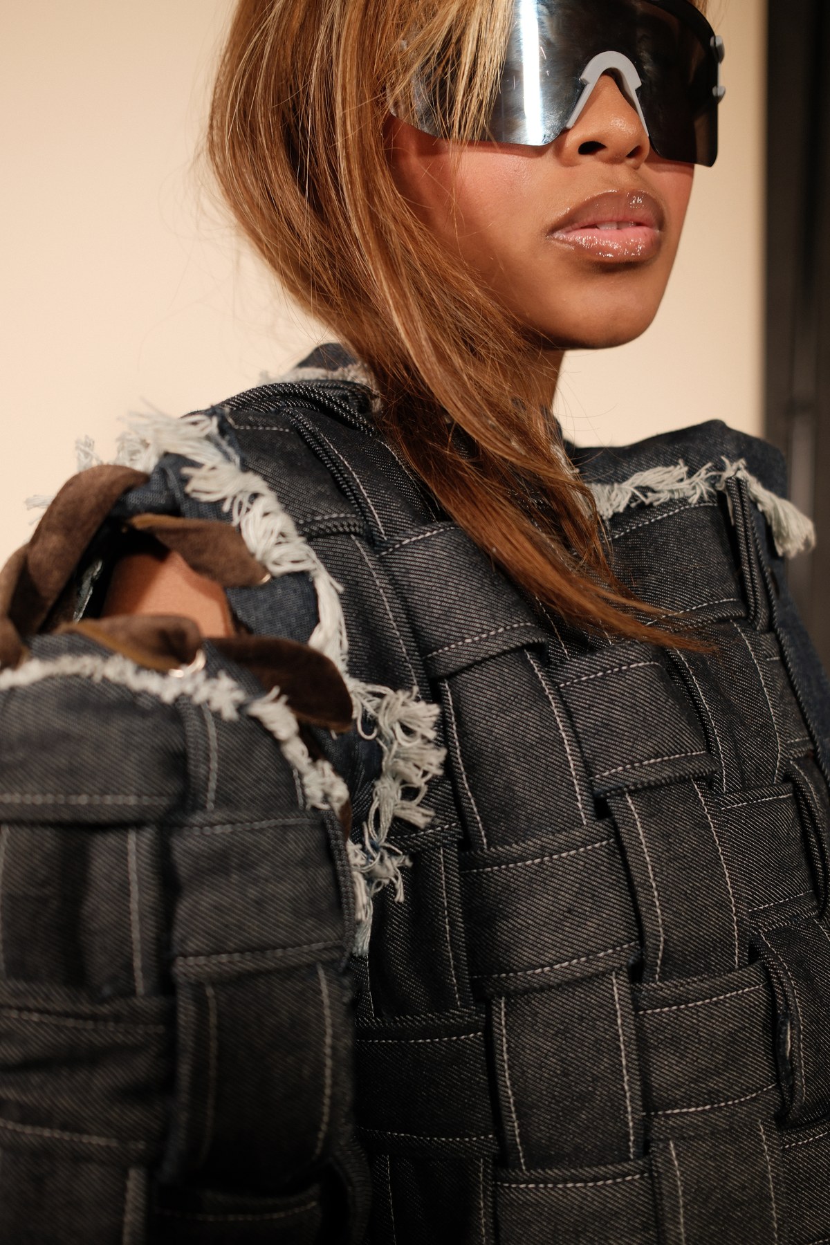 Designed by Mihlali Madikane — close detail of the woven denim jacket, with a chrome shield visor and raw fringing at the seams
