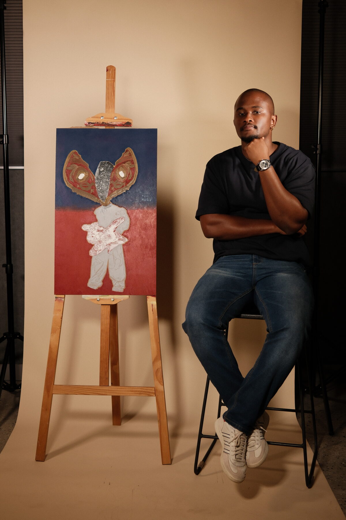 Treasure Mlima seated beside one of his paintings on an easel